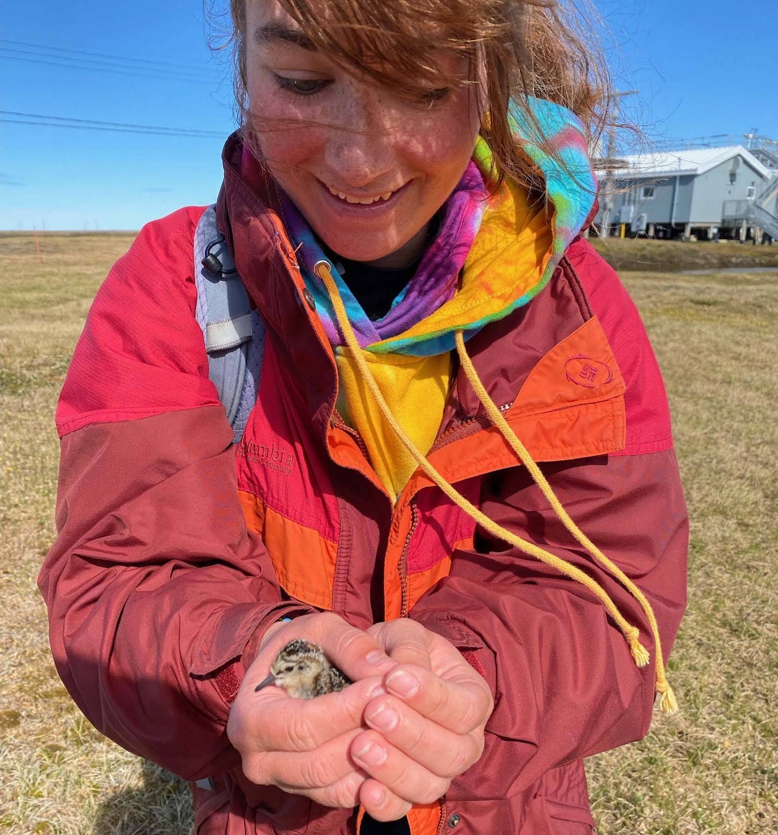 Emma holding a baby bird on the tundra
